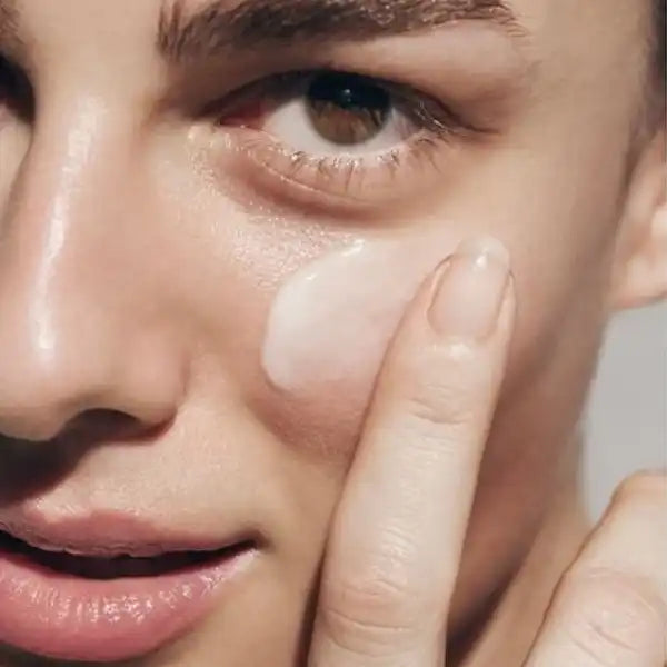 Close-up view of someone applying facial moisturizer or cream with their fingertip.