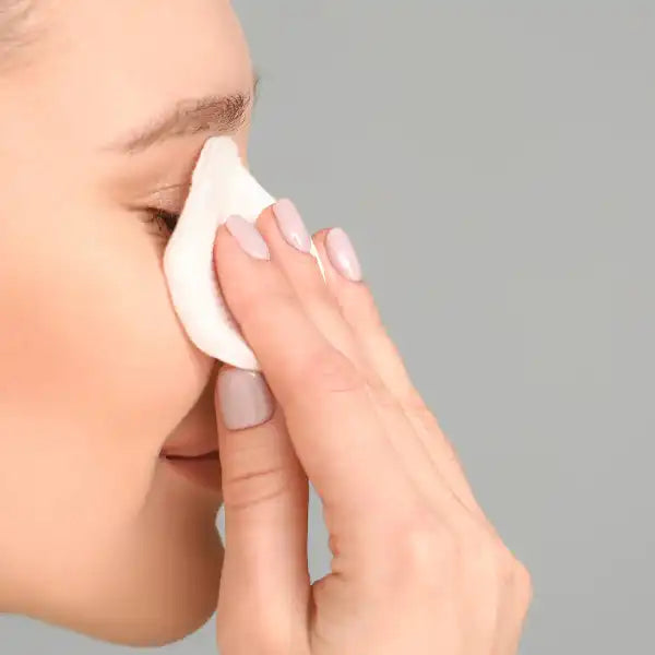 Cotton pad being pressed against a nose with clean manicured fingers.