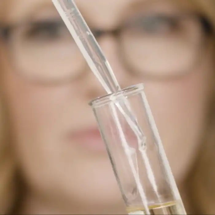 Glass test tube or vial containing liquid with a dropper pipette.