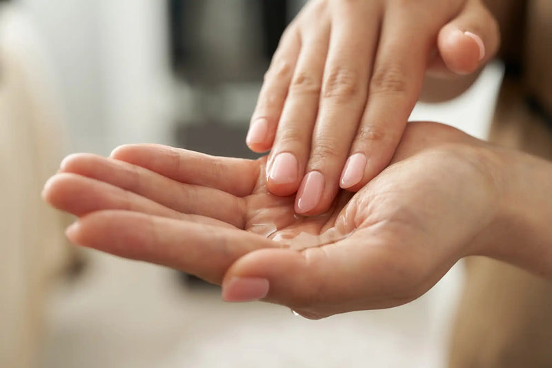 Two hands with well-manicured nails gently touching palm-to-palm.