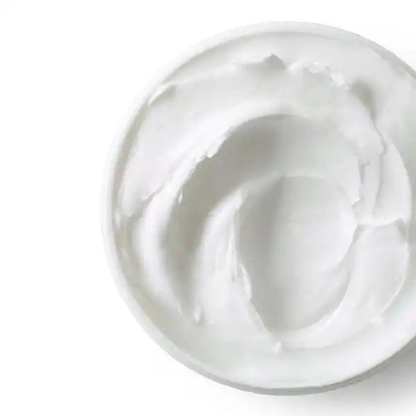 White, creamy moisturizer with a swirled texture in a container.