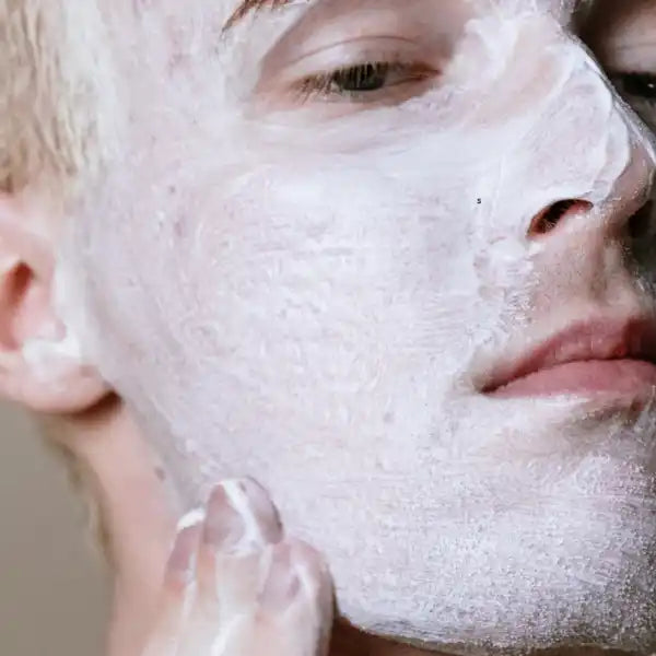 White facial cleanser or exfoliating mask being applied to skin.